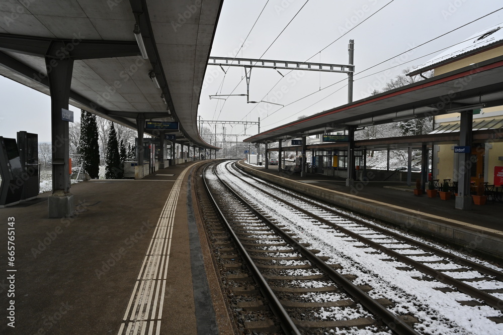 Railway platform of a small village station in winter. There is snow on the railway tracks. 