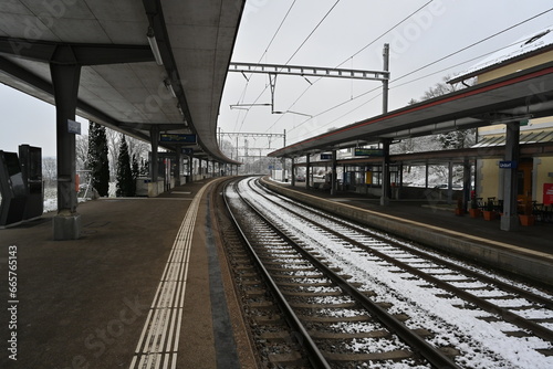 Railway platform of a small village station in winter. There is snow on the railway tracks. 