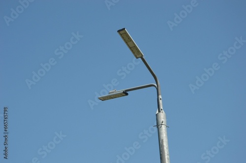 Public street lighting pole with two LED lights on a blue sky background.