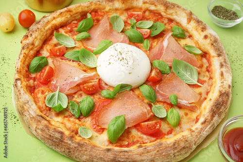 Tasty pizza with Burrata cheese on green background