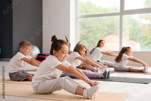 Group of little children practicing yoga in gym