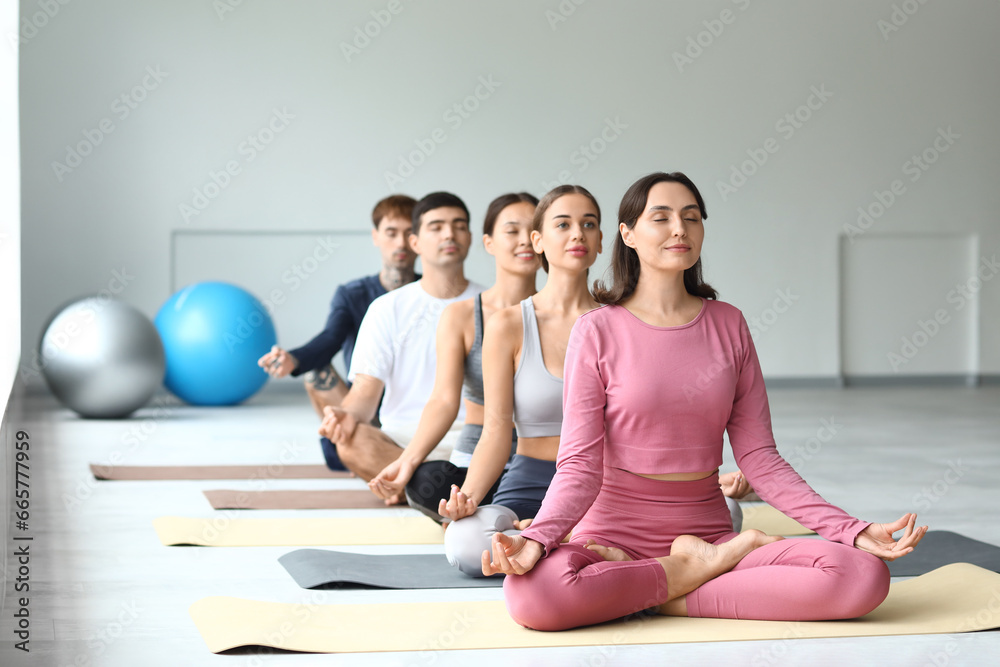 Group of sporty young people meditating in gym Group of sporty young people meditating in gym
