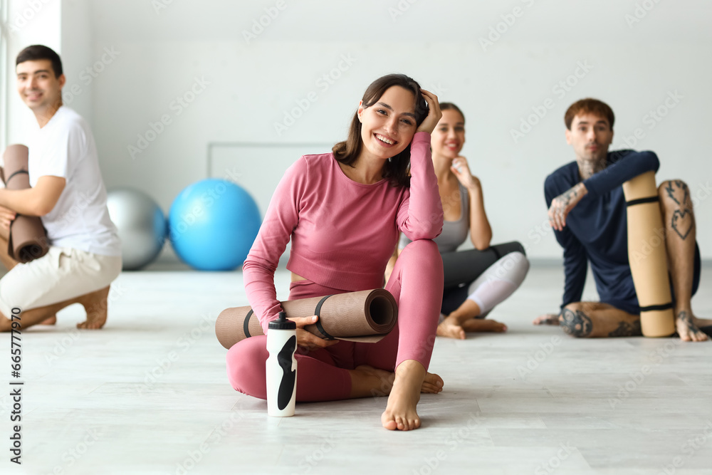 Fototapeta premium Sporty young woman with yoga mat in gym