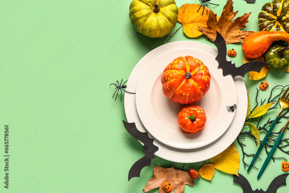 Halloween table setting with pumpkins, leaves and decor on green background