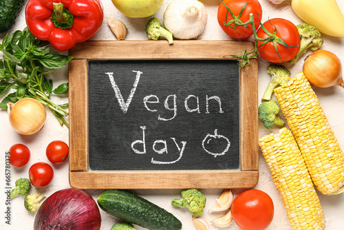 Board with text VEGAN DAY and fresh vegetables on white background