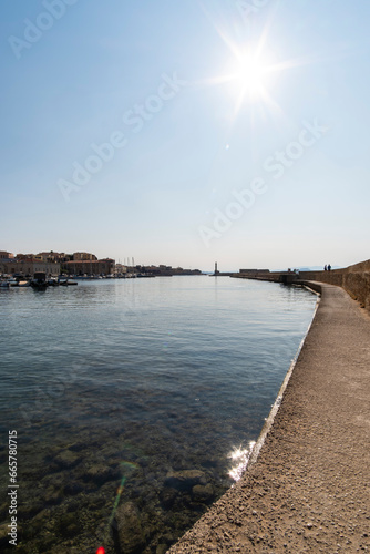 Sun flare shining on a pier walk with quiet water dock in Chania  Crete  touristic Greek Island