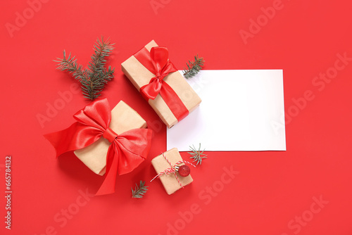 Composition with blank card, Christmas gifts and fir branches on red background