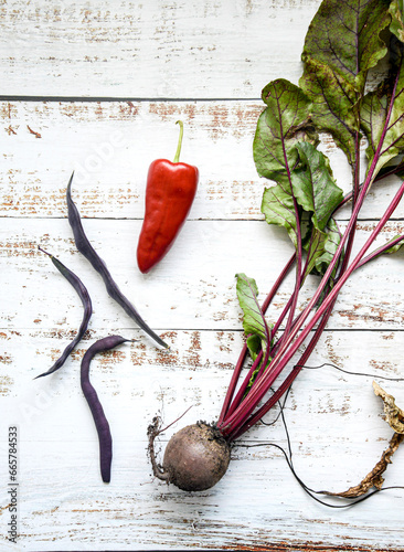 Fresh garden vegetables: beet, purple beans and red pepper on wooden background