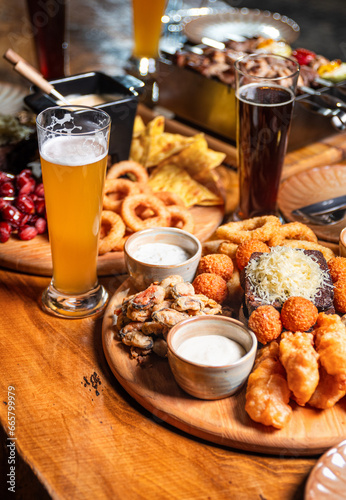 Beer appetizer assorted salted peanuts, sausages and croutons with garlic in a plate on a wooden table. Vertical orientation, close-up, no people