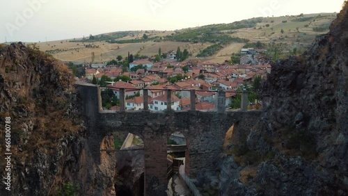 Passing through a valley, the camera passes over the historical aqueduct and moves towards a traditional neighborhood. On the opposite side, you see the vehicles lined up for the wedding convoy follow photo