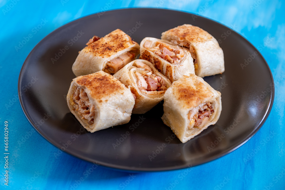 Shawarma pieces on black plate with blue background isolation  and copy space