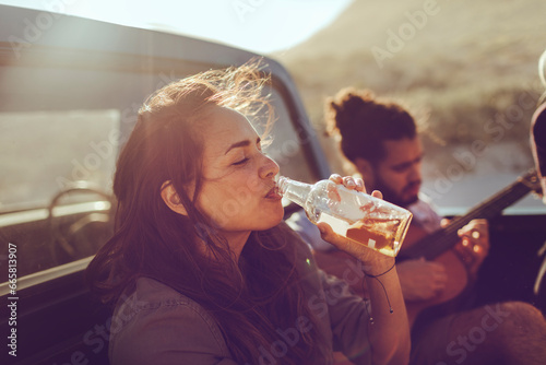 Young woman having a drink on a trip with her friends