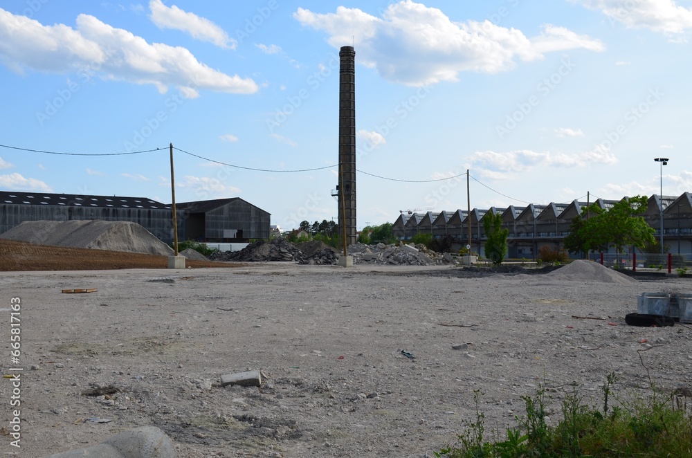 Vacant land where work is beginning with disused buildings, an old chimney and materials construction, perspective view.