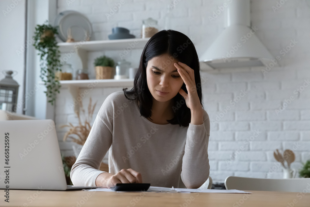 Unhappy stressed Asian woman checking bills, calculating taxes or household expenses, sitting at kitchen table with laptop, frustrated young female tenant renter having money problem, planning budget Unhappy stressed Asian woman checking bills, calculating taxes or household expenses, sitting at kitchen table with laptop, frustrated young female tenant renter having money problem, planning budget