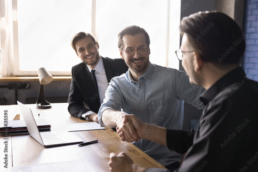 Happy businessmen make deal shake hands finish meeting, boss greeting company client handshaking, express regard, start formal appointment in conference room. Conclude the deal, successful cooperation - obrazy, fototapety, plakaty 