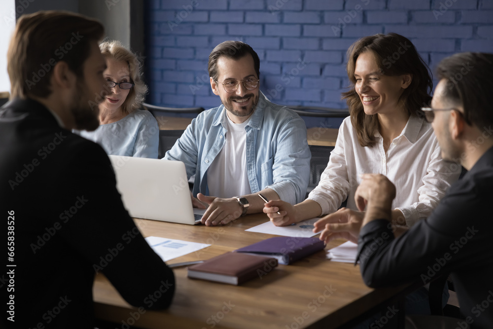 Five happy employees sit at table in boardroom, having pleasant informal conversation, discuss project at meeting or brainstorming. Colleagues enjoy good work relations, have fun, joking, negotiating Five happy employees sit at table in boardroom, having pleasant informal conversation, discuss project at meeting or brainstorming. Colleagues enjoy good work relations, have fun, joking, negotiating