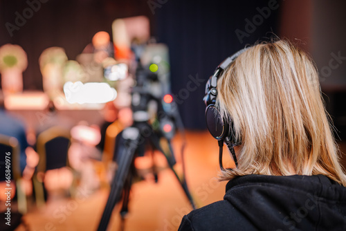 With a soft focus through the video camera's lens, the videographer is seen in a close-up shot, while a skilled woman operator operates the equipment
