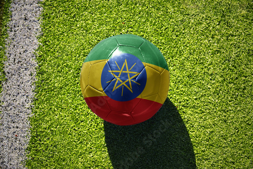 football ball with the flag of ethiopia on the green field near the white line