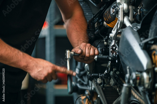 hands of professional person or mechanic working in workshop or garage with tools for auto or bike repair