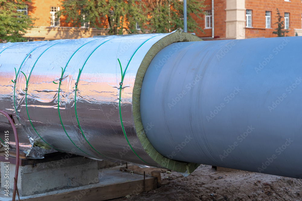 A fragment of a city central heating pipe with thermal or heat insulation. The large diameter city heating pipe. The new pipeline for supplying hot water and heating. Renovation of urban environment A fragment of a city central heating pipe with thermal or heat insulation. The large diameter city heating pipe. The new pipeline for supplying hot water and heating. Renovation of urban environment