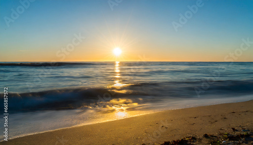 ocean sunrise over beach shore and waves the sun is rising up over sea horizon