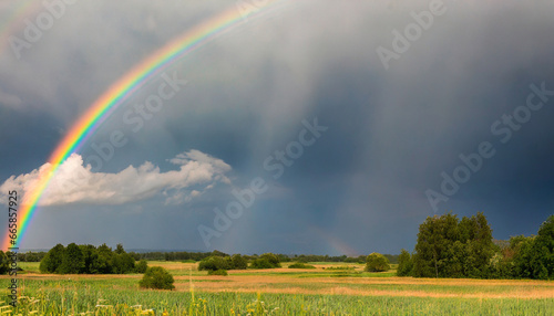 rainbow over stormy sky rural landscape with rainbow over dark stormy sky in a countryside at summer day