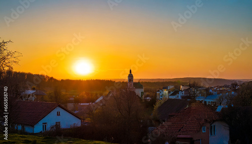 sunset over a little town orange sunbeams illuminate the houses beautiful time of a springday