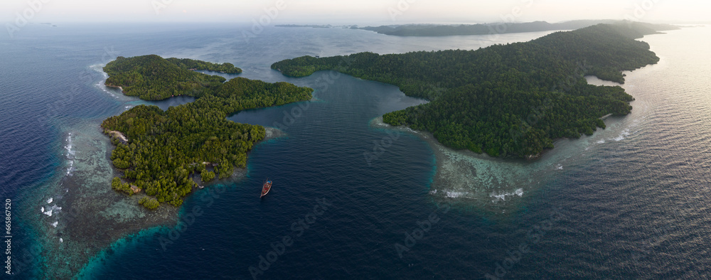 Tropical forest is fringed by coral reefs at Yangeffo Island in Raja Ampat. This area is known as the heart of the Coral Triangle due to its incredible marine biodiversity.