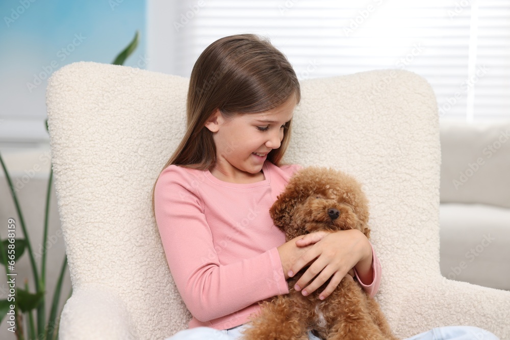 Little child with cute puppy in armchair at home. Lovely pet Little child with cute puppy in armchair at home. Lovely pet