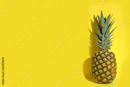 Whole ripe pineapple on yellow background, space for text
