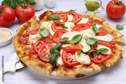 Delicious Caprese pizza with tomatoes, mozzarella and basil served on white tiled table, closeup