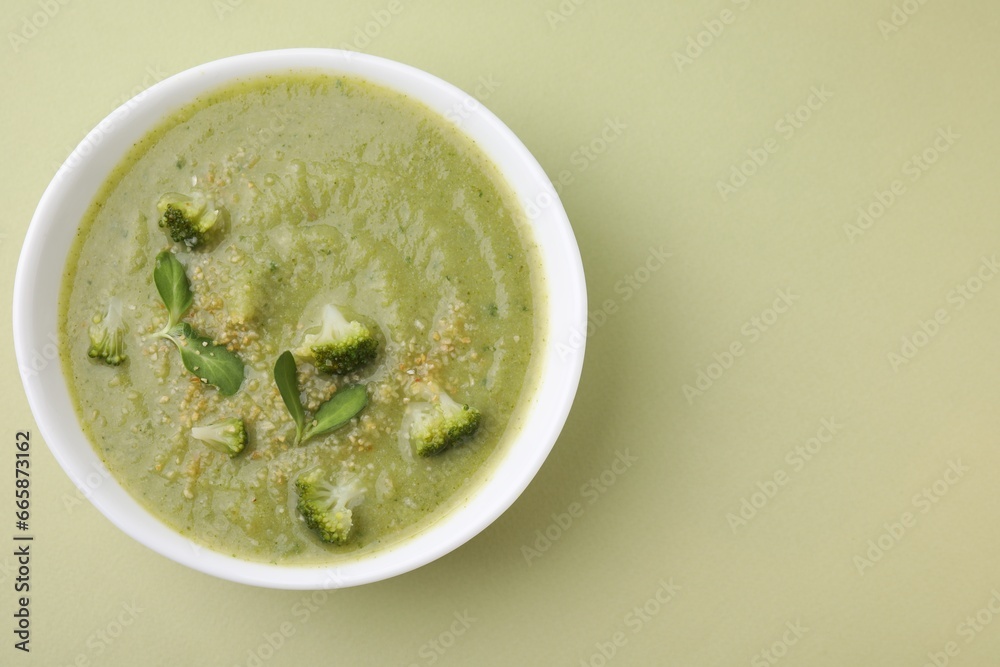 Delicious broccoli cream soup on olive background, top view. Space for text Delicious broccoli cream soup on olive background, top view. Space for text