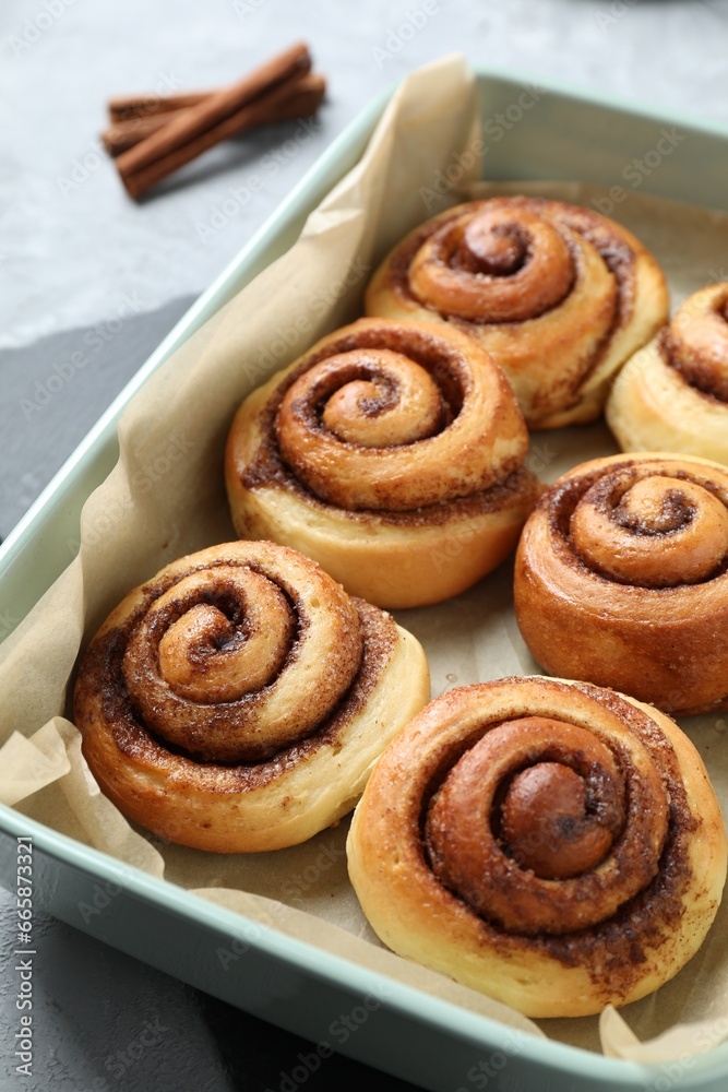 Baking dish with tasty cinnamon rolls on grey table, closeup Baking dish with tasty cinnamon rolls on grey table, closeup