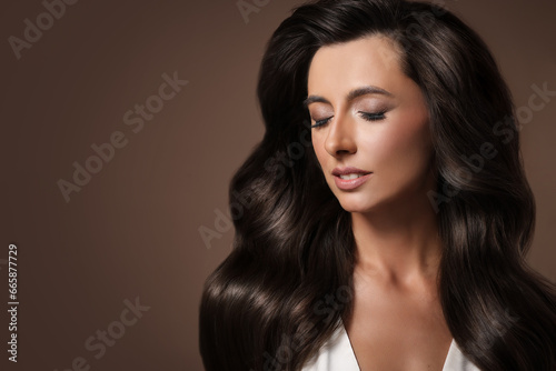Gorgeous woman with shiny wavy hair on brown background, space for text. Professional hairstyling