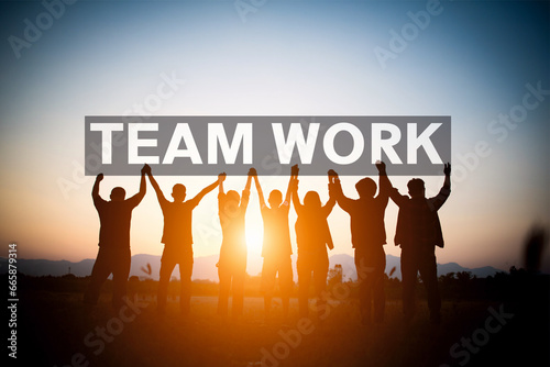 Trabajo en equipo uniendo sus manos en un cartel que dice Team Work al amanecer.