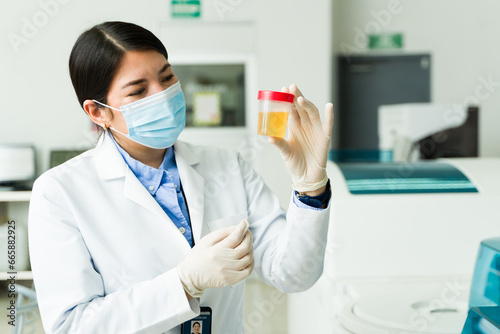 Woman chemist holding a urine test for medical exams in the lab photo