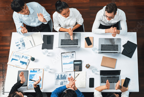 Top view analyst team utilizing BI Fintech to analyze financial data at table in meeting room. Analytic BI dashboard power on paper for business insight and strategic marketing planning. Prudent