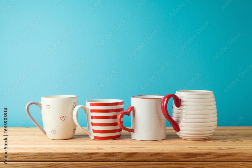 Coffee cups and tea mugs on wooden table over blue background. Kitchen decoration Coffee cups and tea mugs on wooden table over blue background. Kitchen decoration