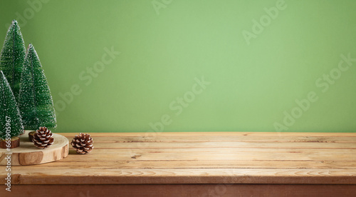 Empty wooden table with pine tree decoration over green background.  Christmas and winter holidays mock up for design and product display