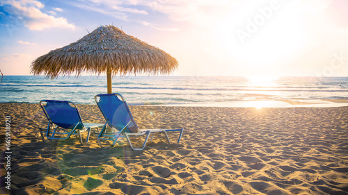 Fototapeta Naklejka Na Ścianę i Meble -  Two Chaise lounges under umbrella on the beach at sunset