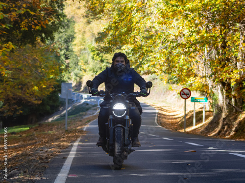 Motorcycle traveling on a road in the middle of an autumn landscape