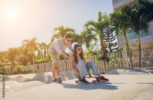 Young happy couple with skateboards enjoy longboarding at the skatepark photo