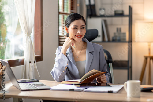 Young business asian woman working at home with laptop and papers on desk