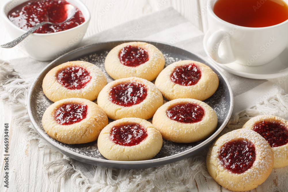 Hallongrottor or Swedish rapsberry caves jam cookies closeup on the plate on the white wooden table. Horizontal