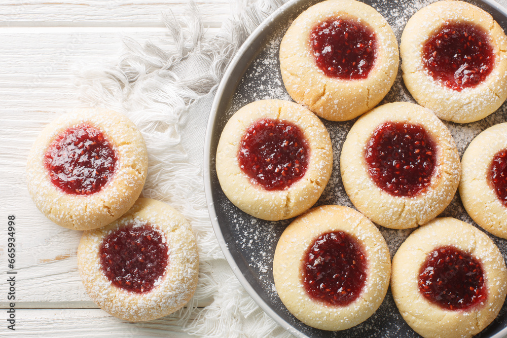 Thumbprint or Hallongrottor Swedish Raspberry Jam Cookies closeup on the plate on the white wooden table. Horizontal top view from above Thumbprint or Hallongrottor Swedish Raspberry Jam Cookies closeup on the plate on the white wooden table. Horizontal top view from above