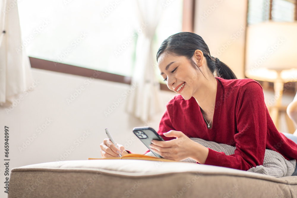 Happy relaxed young woman sitting on couch using cell phone, smiling lady laughing holding smartphone, looking at cellphone enjoying doing online ecommerce shopping in mobile apps or watching videos. Happy relaxed young woman sitting on couch using cell phone, smiling lady laughing holding smartphone, looking at cellphone enjoying doing online ecommerce shopping in mobile apps or watching videos.