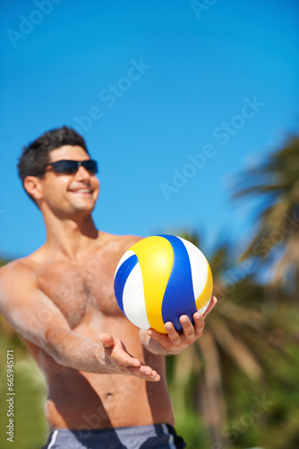 Volleyball, sports and happy fitness man at a beach with ball serve, energy or freedom on blue sky background. Smile, sports or male player with handball in nature for workout, game or performance