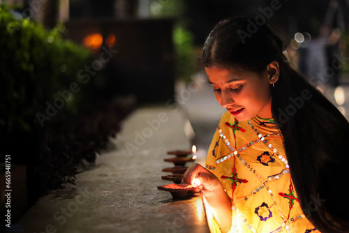 Indian girl lighting the diya for diwali