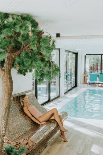 Young woman relaxing by the indoor swimming pool