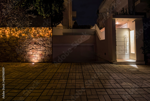 A night view of a contemporary house pedestrian and car entrance with Christmas decorated fence. Athens  Greece..